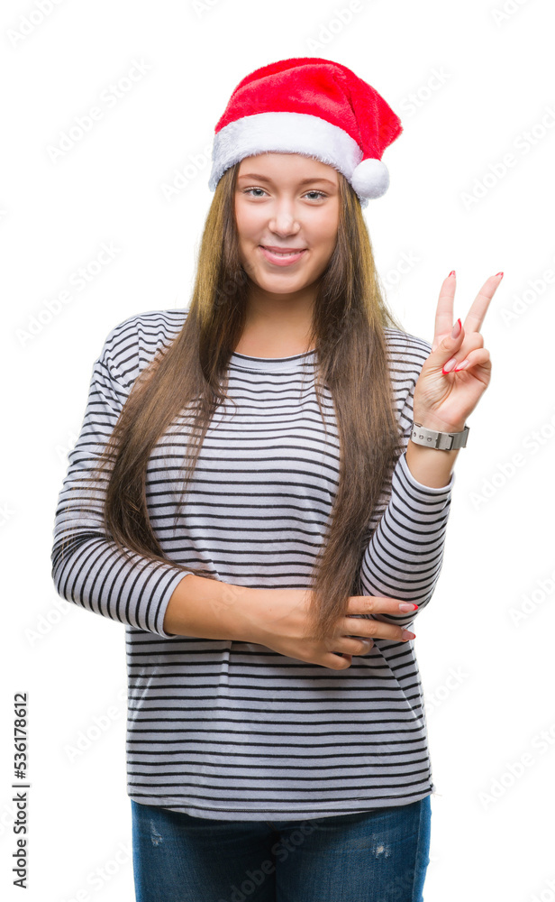 Young beautiful caucasian woman wearing christmas hat over isolated background smiling with happy face winking at the camera doing victory sign. Number two. Young beautiful caucasian woman wearing christmas hat over isolated background smiling with happy face winking at the camera doing victory sign. Number two.