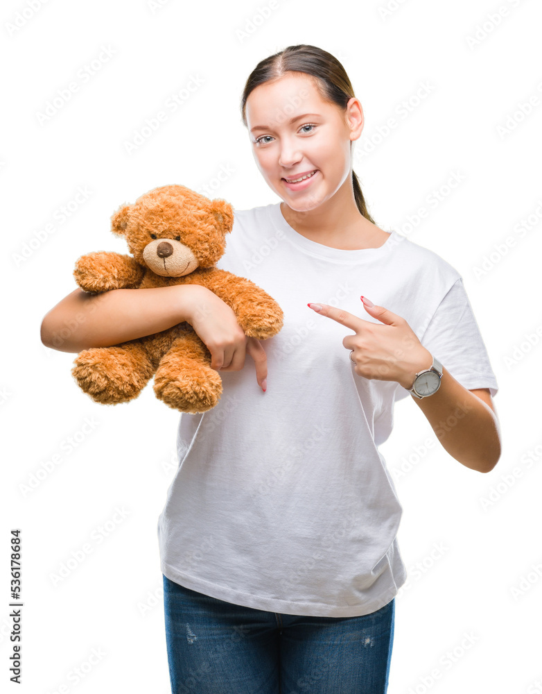 Young caucasian woman holding teddy bear over isolated background very happy pointing with hand and finger Young caucasian woman holding teddy bear over isolated background very happy pointing with hand and finger