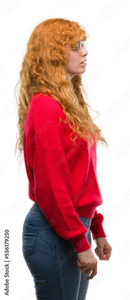 Young redhead woman wearing red sweater looking to side, relax profile pose with natural face with confident smile. Young redhead woman wearing red sweater looking to side, relax profile pose with natural face with confident smile.
