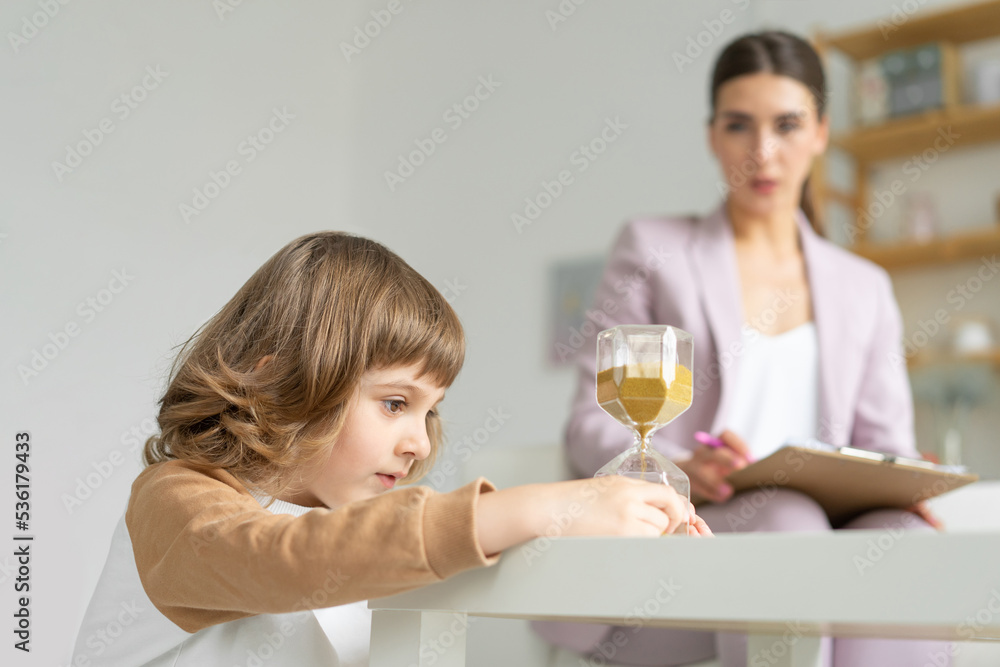 Consultations with a child psychologist. The boy is playing with an hourglass. Copy space Consultations with a child psychologist. The boy is playing with an hourglass. Copy space