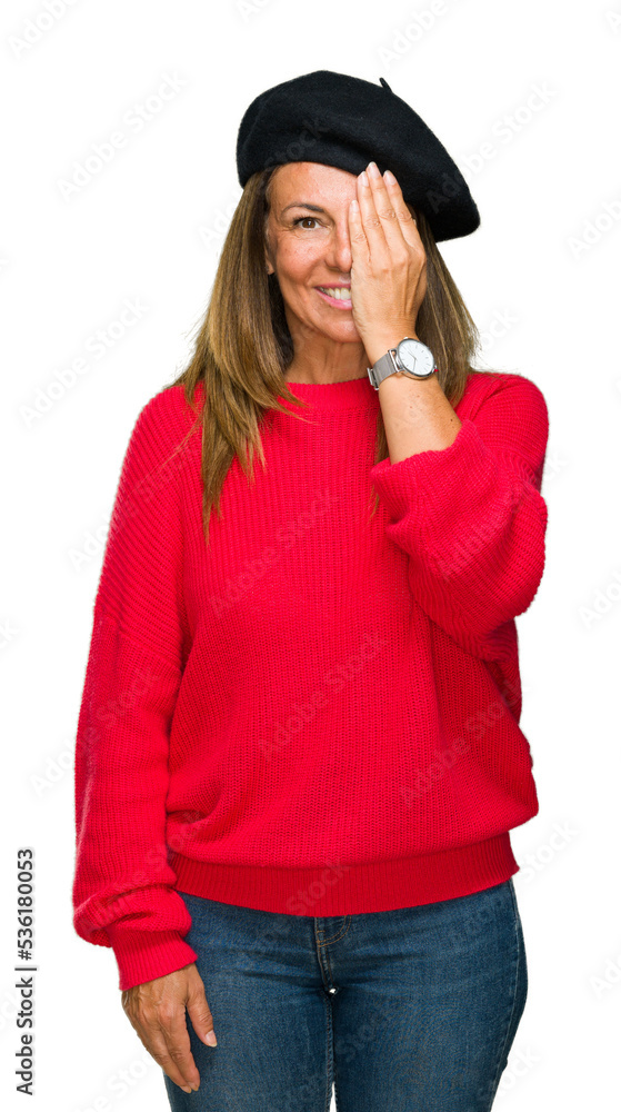 Middle age adult woman wearing fashion beret over isolated background covering one eye with hand with confident smile on face and surprise emotion. Middle age adult woman wearing fashion beret over isolated background covering one eye with hand with confident smile on face and surprise emotion.