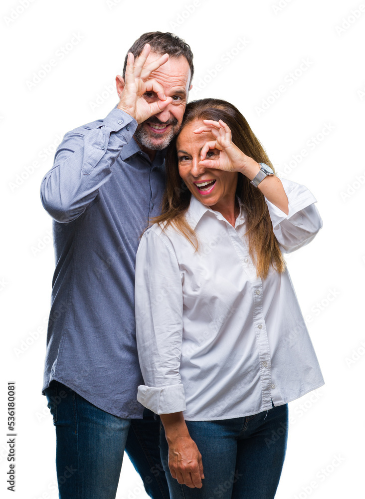 Fototapeta premium Middle age hispanic business couple over isolated background doing ok gesture with hand smiling, eye looking through fingers with happy face.