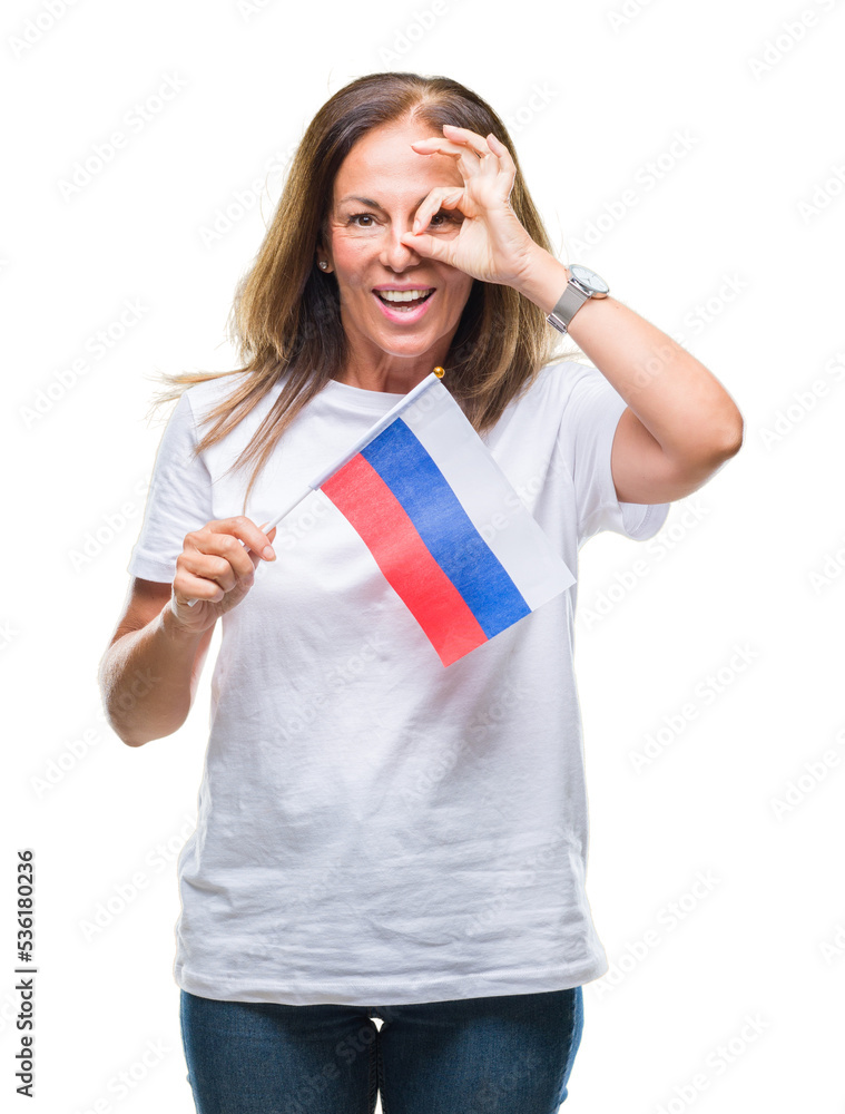Fototapeta premium Middle age hispanic woman holding flag of Russia over isolated background with happy face smiling doing ok sign with hand on eye looking through fingers
