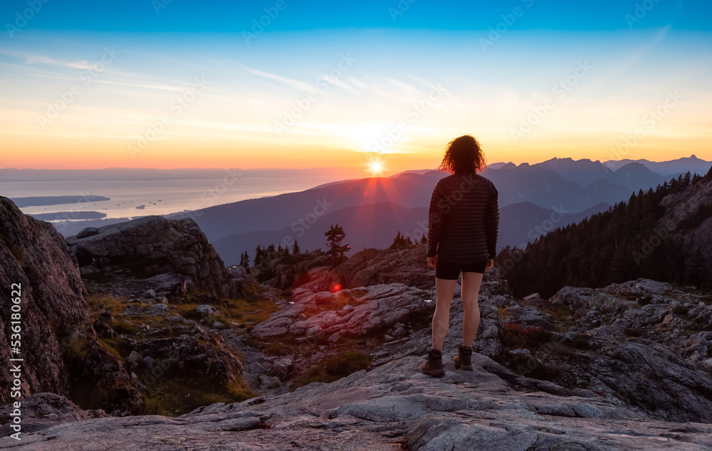 Adventurous Woman Hiker on top of Canadian Mountain Landscape. Sunny Sunset Sky. Top of Mt Seymour near Vancouver, British Columbia, Canada. Adventure Travel Concept