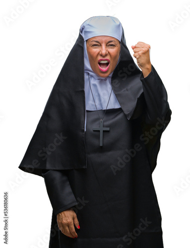 Middle age senior christian catholic nun woman over isolated background angry and mad raising fist frustrated and furious while shouting with anger. Rage and aggressive concept.