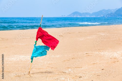Position Mark Flag at Landscape / Red and blue signal flags pinned on beach sand at sunny coast (copy space)