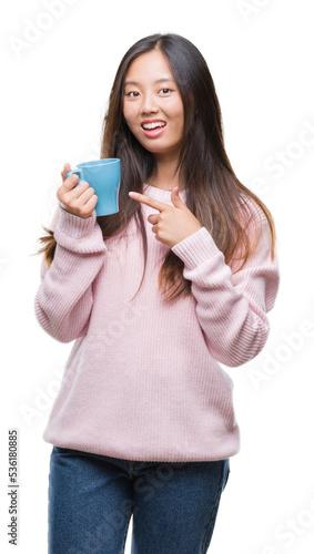 Young asian woman drinking coffee over isolated background very happy pointing with hand and finger
