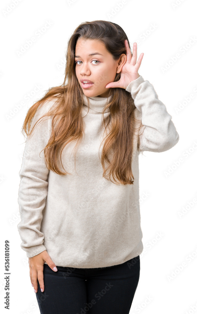 Young beautiful brunette woman wearing turtleneck sweater over isolated background smiling with hand over ear listening an hearing to rumor or gossip. Deafness concept. Young beautiful brunette woman wearing turtleneck sweater over isolated background smiling with hand over ear listening an hearing to rumor or gossip. Deafness concept.