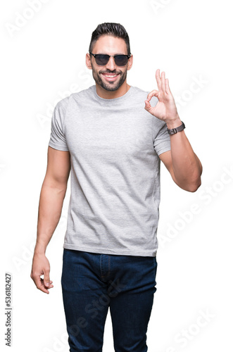 Young handsome man wearing sunglasses over isolated background doing ok sign with fingers, excellent symbol © Krakenimages.com