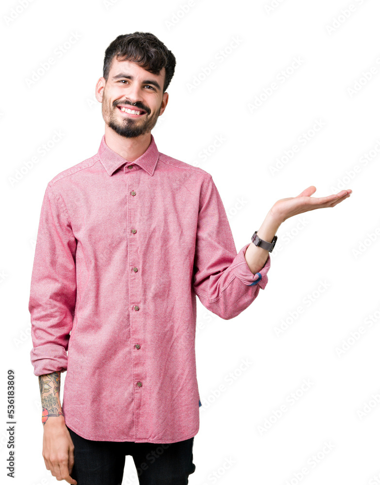 Young handsome man wearing pink shirt over isolated background smiling cheerful presenting and pointing with palm of hand looking at the camera.