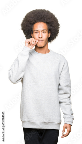 Принти на полотні Young african american man with afro hair wearing sporty sweatshirt mouth and lips shut as zip with fingers