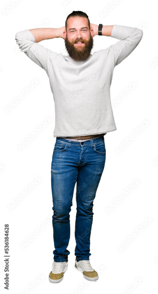 Young blond man wearing casual sweater Relaxing and stretching with arms and hands behind head and neck, smiling happy Young blond man wearing casual sweater Relaxing and stretching with arms and hands behind head and neck, smiling happy