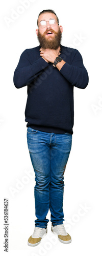 Young blond man wearing glasses and turtleneck sweater shouting and suffocate because painful strangle. Health problem. Asphyxiate and suicide concept.