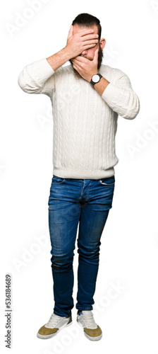 Young hipster man wearing winter sweater Covering eyes and mouth with hands, surprised and shocked. Hiding emotion