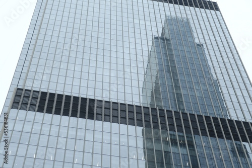 Modern skyscraper with glass windows. From below of contemporary tall building with reflection of skyscraper.