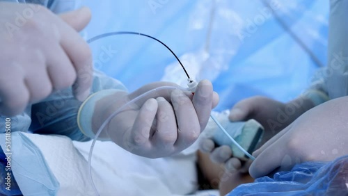 Male gloved hands holding and using the surgical tools and devices. Close up. Vascular operation in process.