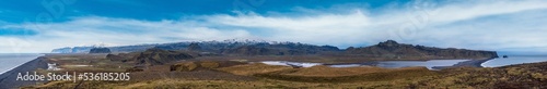 Picturesque autumn evening ultrawide panorama to endless ocean black volcanic sand beach and to Reynisfjara beach  from Dyrholaey Cape Viewpoint, Vik, South Iceland.