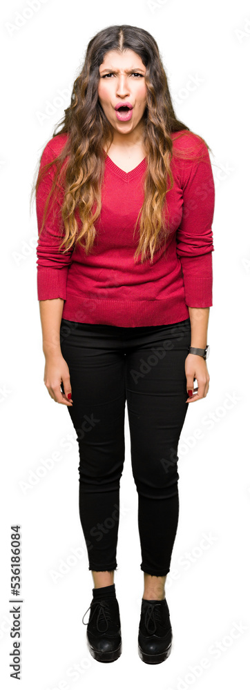 Obraz premium Young beautiful woman wearing red sweater afraid and shocked with surprise expression, fear and excited face.