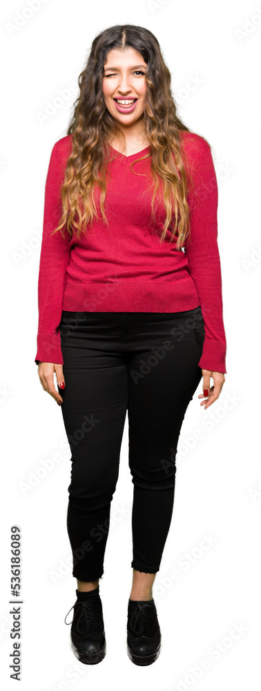 Obraz premium Young beautiful woman wearing red sweater winking looking at the camera with sexy expression, cheerful and happy face.