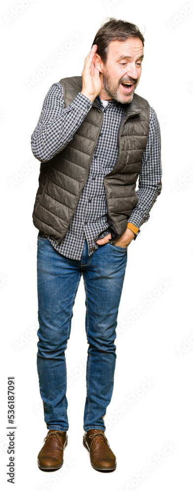 Fototapeta premium Middle age handsome man wearing winter vest smiling with hand over ear listening an hearing to rumor or gossip. Deafness concept.