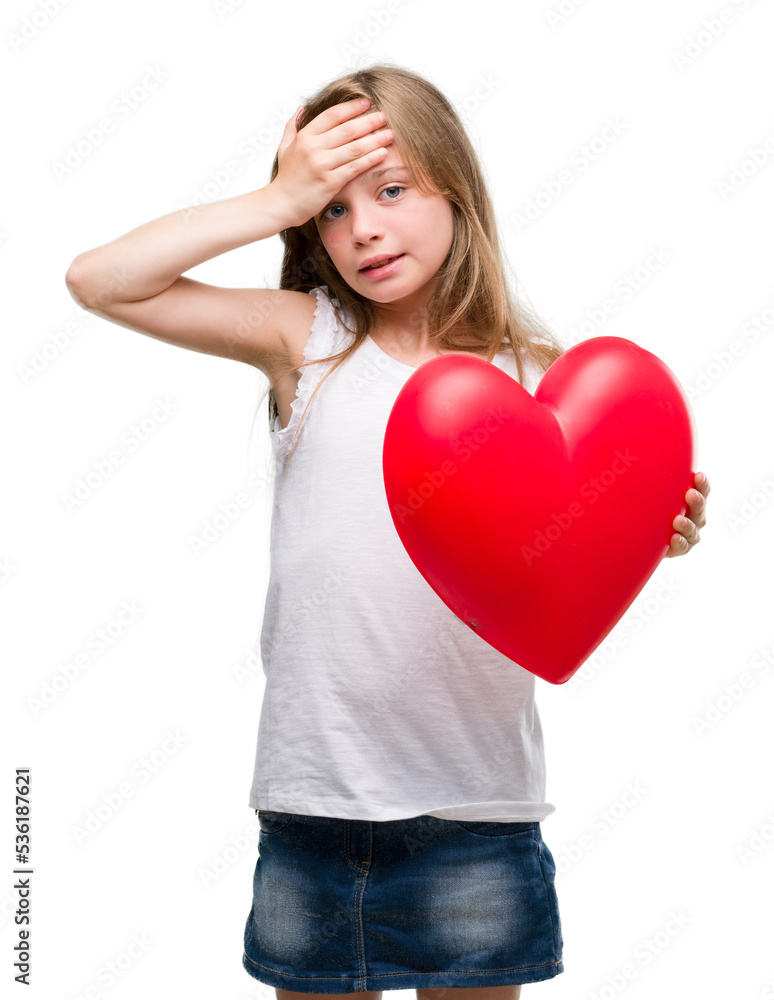 Young blonde toddler holding a red heart stressed with hand on head, shocked with shame and surprise face, angry and frustrated. Fear and upset for mistake. Young blonde toddler holding a red heart stressed with hand on head, shocked with shame and surprise face, angry and frustrated. Fear and upset for mistake.