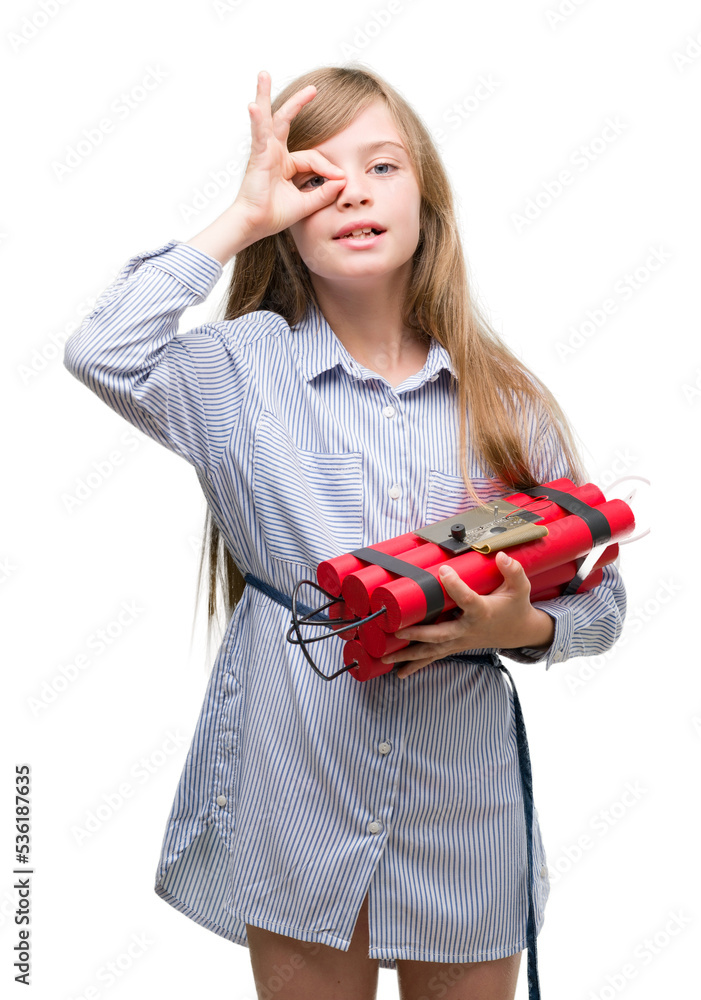 Young blonde child holding dynamite bomb with happy face smiling doing ok sign with hand on eye looking through fingers Young blonde child holding dynamite bomb with happy face smiling doing ok sign with hand on eye looking through fingers
