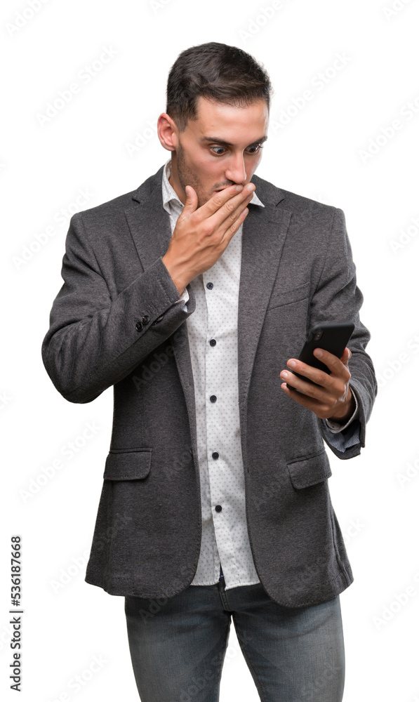 Handsome young man using smartphone cover mouth with hand shocked with shame for mistake, expression of fear, scared in silence, secret concept Handsome young man using smartphone cover mouth with hand shocked with shame for mistake, expression of fear, scared in silence, secret concept