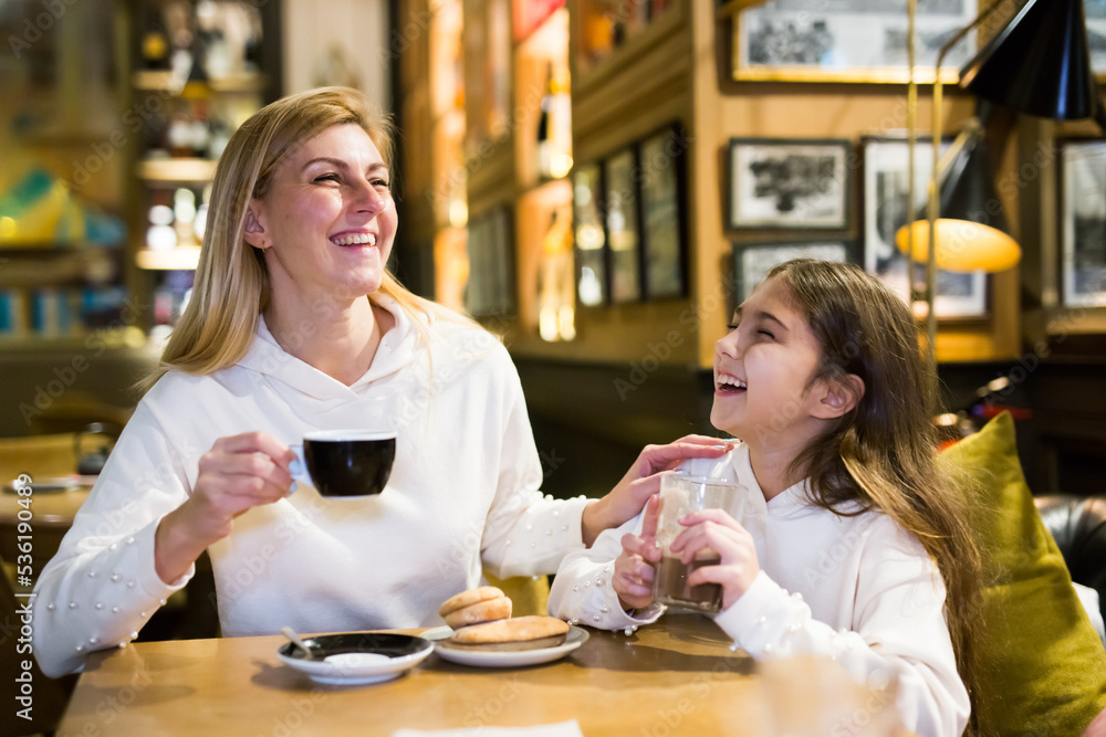 Portrait of happy mother and teenage daughter drinking tea in a cafe