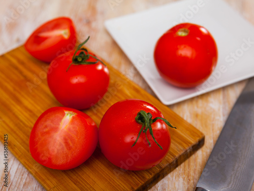 Fresh ripe tomatoes ready for cooking on wooden background at kitchen