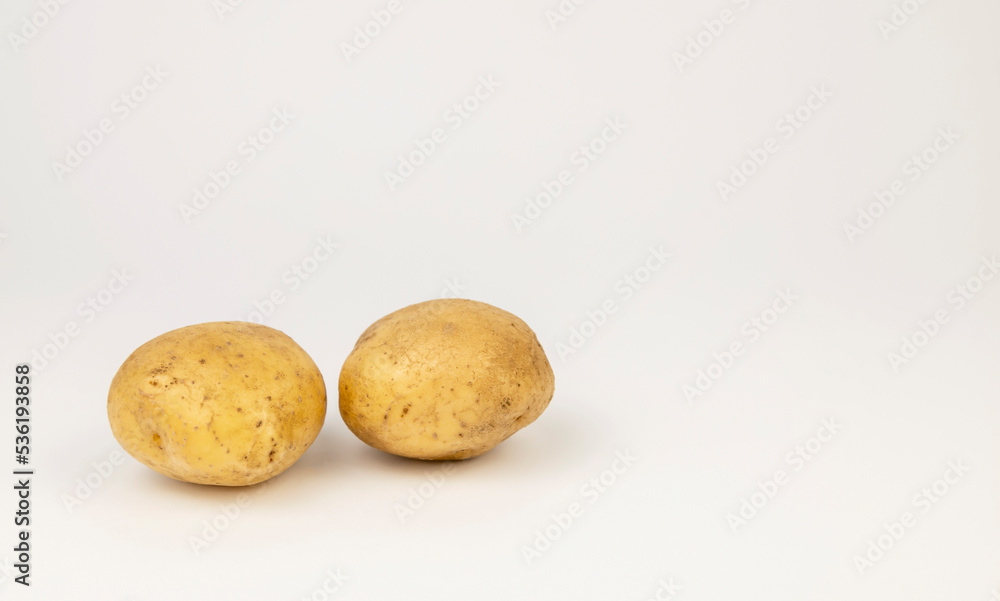Two fresh young potatoes isolated on a white background. Two fresh young potatoes isolated on a white background.
