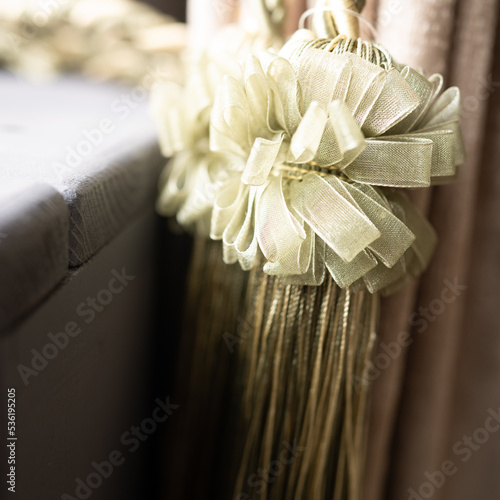 Texture of synthetic golden threads. Gold tassels made of cord, ropes on curtains with bows made of silk ribbonHigh quality photo