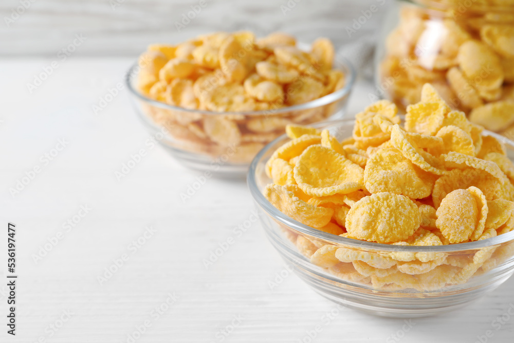 Glass bowl of tasty crispy corn flakes on white wooden table, space for text Glass bowl of tasty crispy corn flakes on white wooden table, space for text
