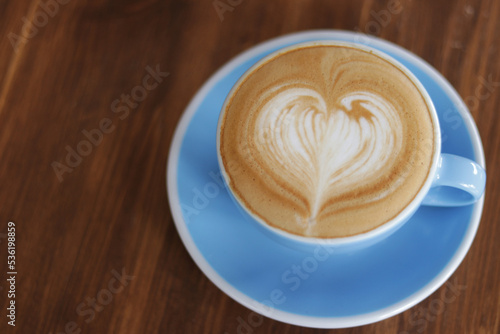 Cup of Latte art coffee in heart shaped on wooden table background. Close up, coffee break.