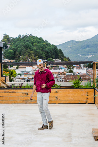 Caucasian peasant walking on a rooftop with an urban vegetable garden and the landscape in the background.