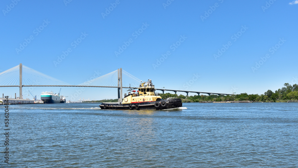 A tugboat plies the water of the Savannah River along the waterfront of the city.