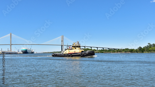 A tugboat plies the water of the Savannah River along the waterfront of the city.
