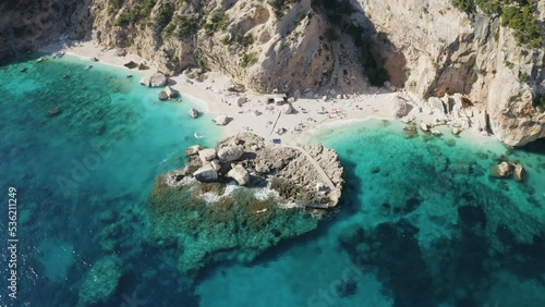 Top view of beautiful beach with turquoise sea water and stone pier. Islands of Sardinia in Italy, aerial drone shot. Summer seascape