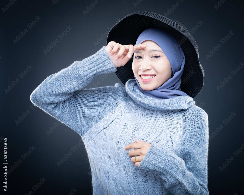 Portrait of a beautiful female model wearing hijab, a lifestyle apparel for Muslim women isolated on brown background. Idul Fitri and hijab fashion concept. Isolated on dark background Portrait of a beautiful female model wearing hijab, a lifestyle apparel for Muslim women isolated on brown background. Idul Fitri and hijab fashion concept. Isolated on dark background
