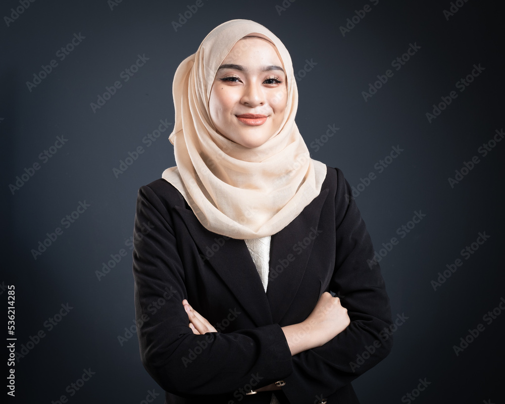 Confident Muslim woman wearing hijab poses strongly and confidently. Women empowerment and leadership concept. Isolated on dark background Confident Muslim woman wearing hijab poses strongly and confidently. Women empowerment and leadership concept. Isolated on dark background