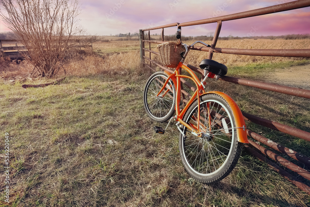 Orange bicycle at the entrance to a bike trail in the countryside
