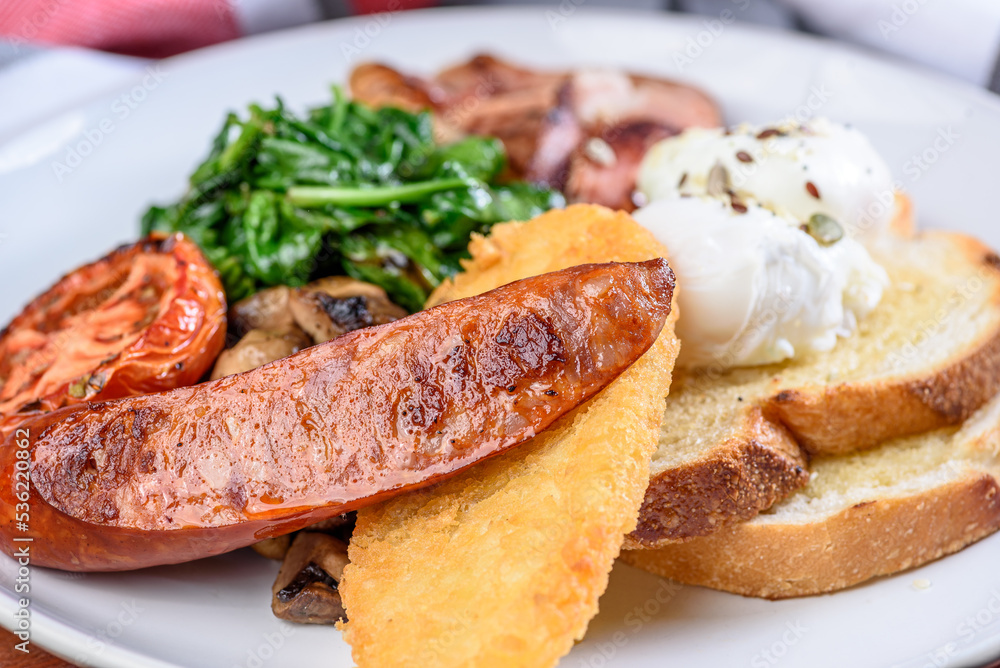 A serving of country breakfast consisting of bacon, tomato, eggs, toast, mushrooms, spinach, spinach and a hash brown A serving of country breakfast consisting of bacon, tomato, eggs, toast, mushrooms, spinach, spinach and a hash brown