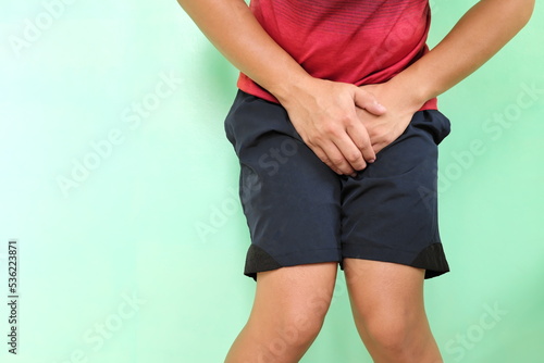 Urinary incontinence, UTI and control urine in male concept. Young asian athlete man grabbing his groin with copy space.	 photo