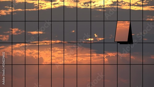 Sunset clouds mirrored in glass windows facade of business skyscraper building