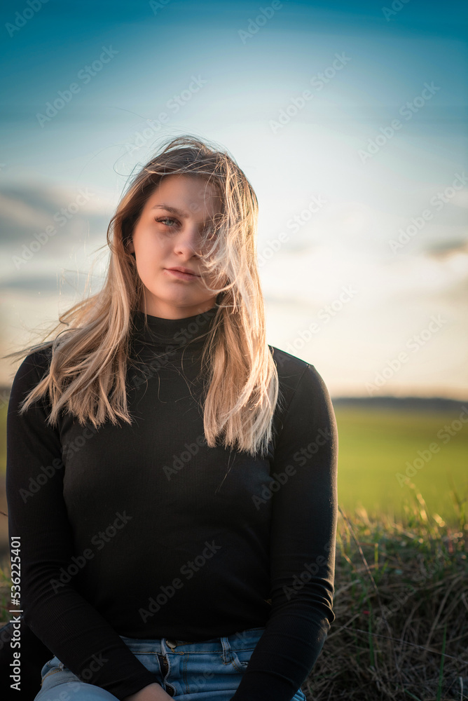 Portrait of a young beautiful blonde girl outdoors. There is artistic noise.