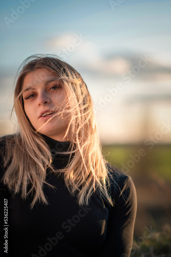 Portrait of a young beautiful blonde girl outdoors. There is artistic noise.