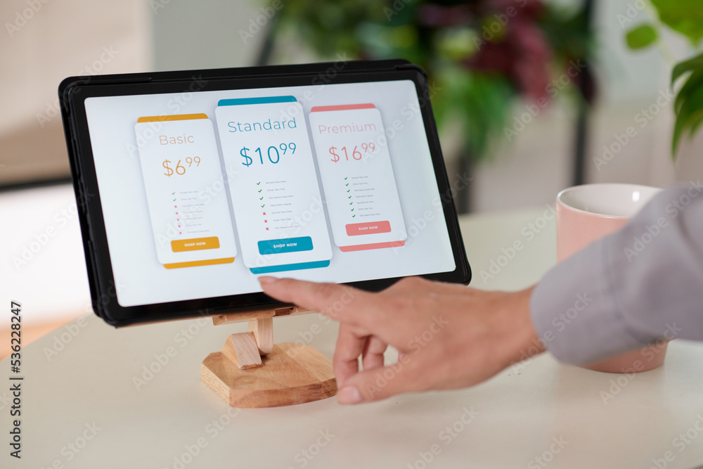 Hand of young female customer pointing at model of smartphone on tablet screen Hand of young female customer pointing at model of smartphone on tablet screen