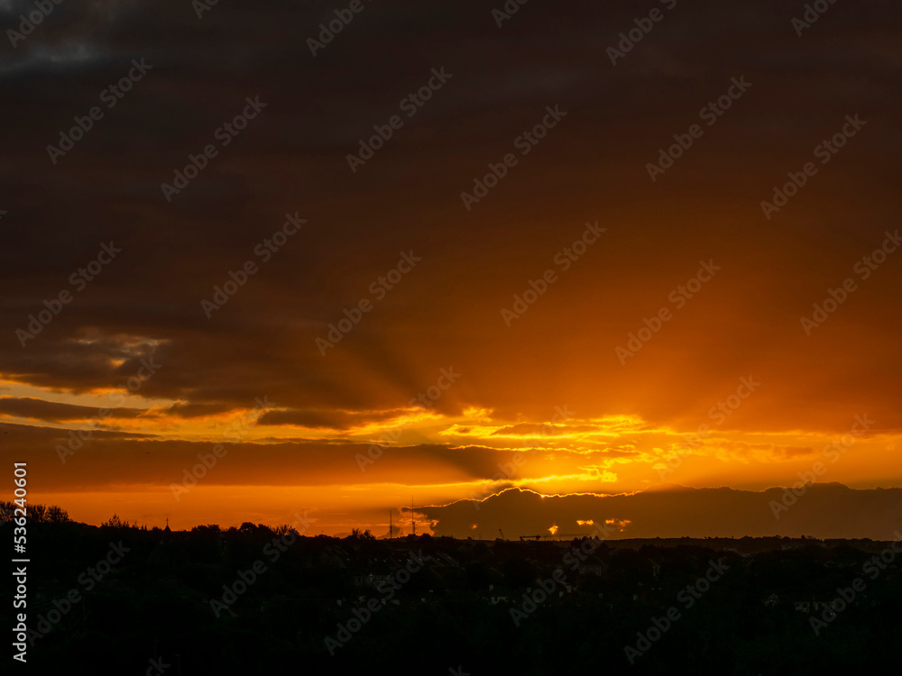 Dramatic sunset nature scene. Warm orange color sky with sun rays and flare. Stunning nature scene at dusk.