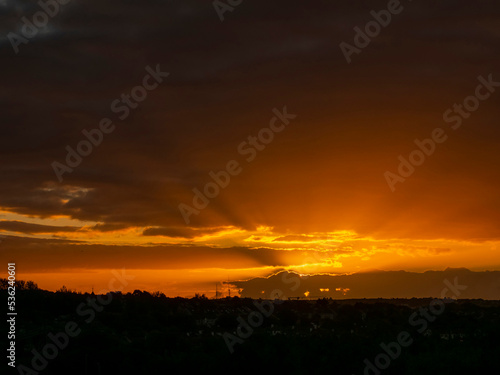 Dramatic sunset nature scene. Warm orange color sky with sun rays and flare. Stunning nature scene at dusk.