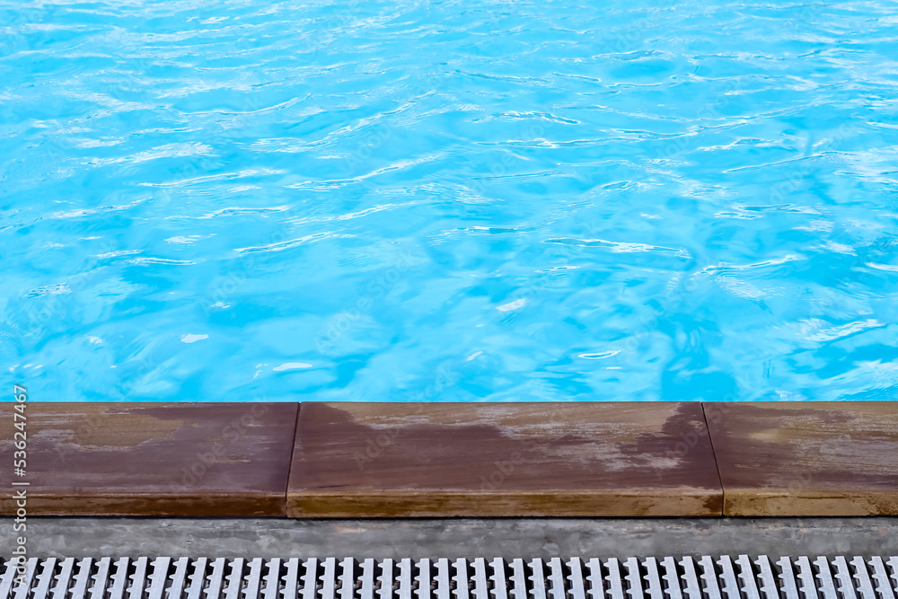 Blue swimming pool and wood plank edge on background