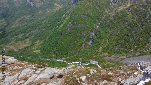 Spectacular nature with river flowing valley towards Leiro freshwater lake above Eidslandet in Vaksdal Norway - Aerial with parallax effect at steep mountain cliff before revealing lake and village photo